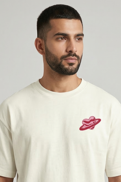 Man wearing a Ivory t-shirt with a pink heart logo on left side of chest.